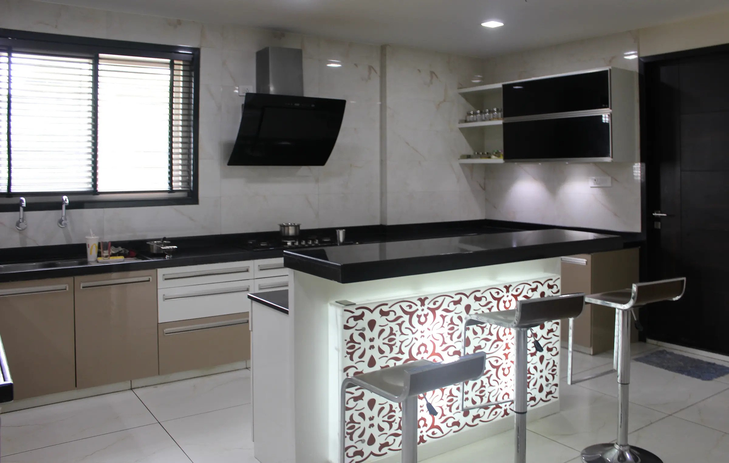 Kitchen with a backlit breakfast counter in a laser-cut pattern and black bar stools