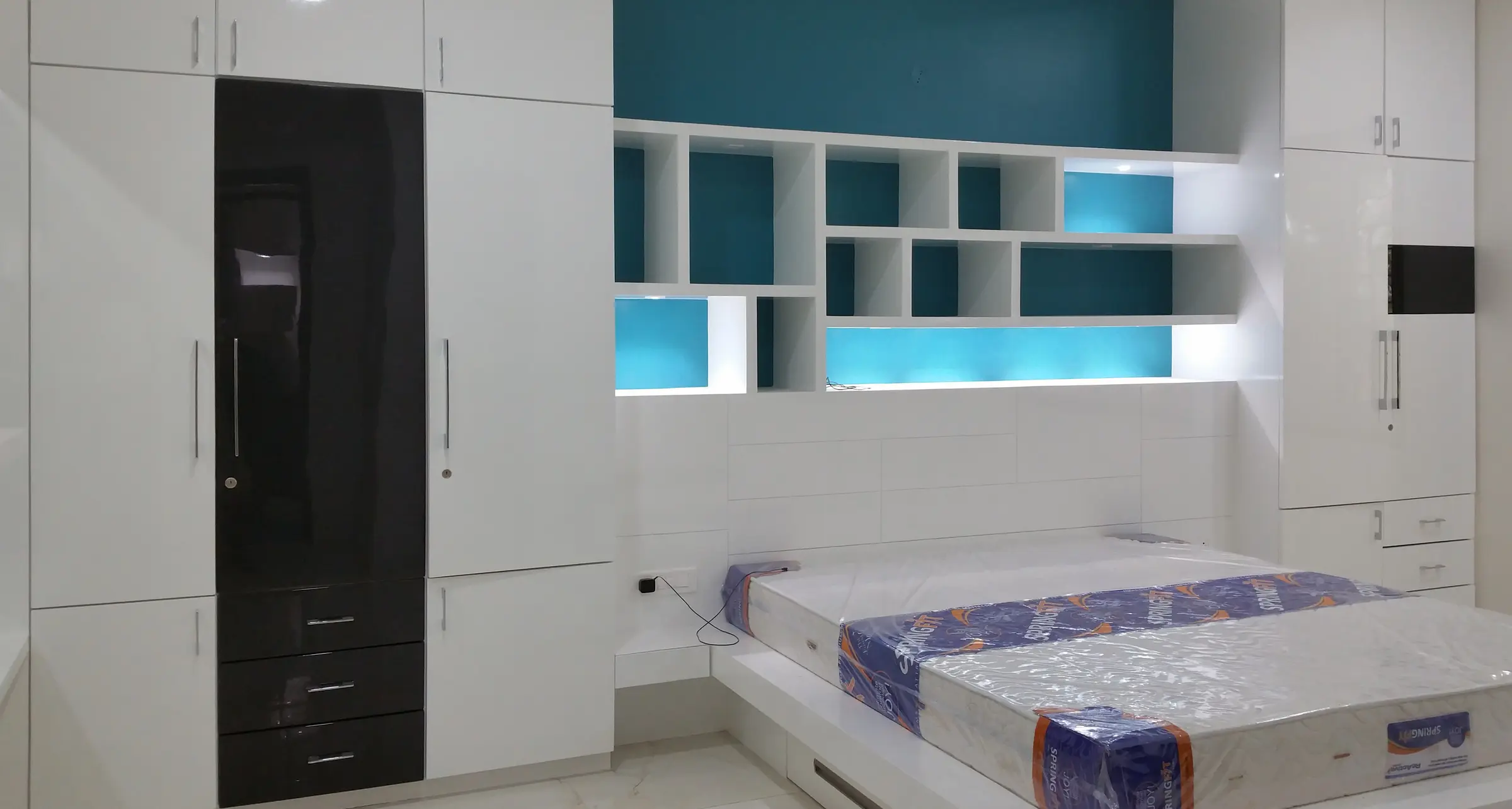 Children's room with white wardrobes and teal display shelves around the bed