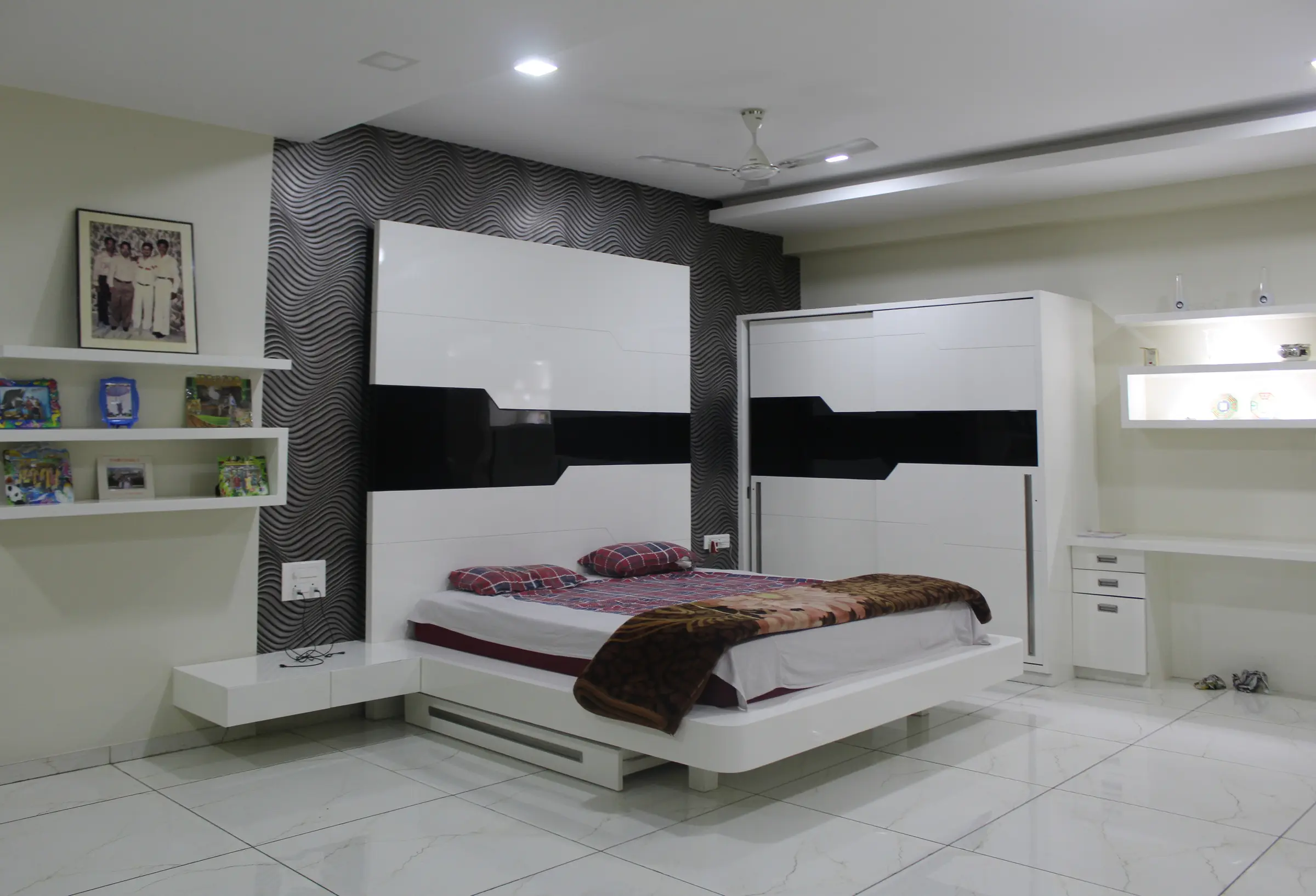 Bedroom with a black and white headboard wall, floating shelves and a study desk