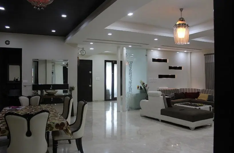 Dining area with patterned upholstered chairs under a black ceiling panel and pendant light