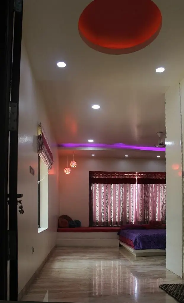 Bedroom seen from the corridor, lit by a red ceiling disc and purple cove lights
