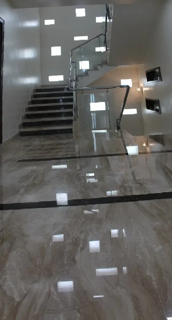 Staircase with glass railings and square wall lights reflected in the polished floor