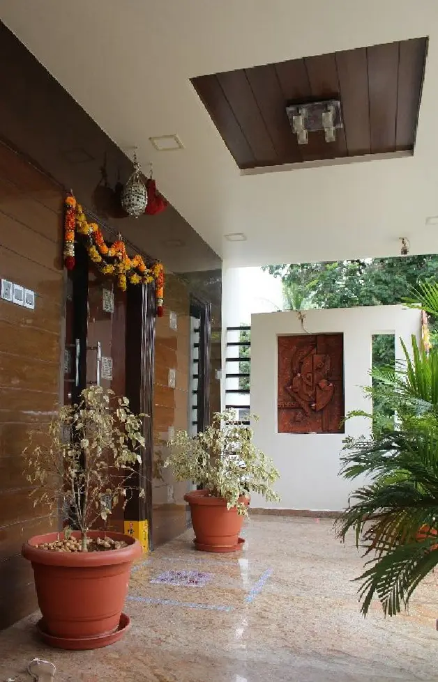 Entrance porch with potted plants, a carved timber panel and a garlanded door