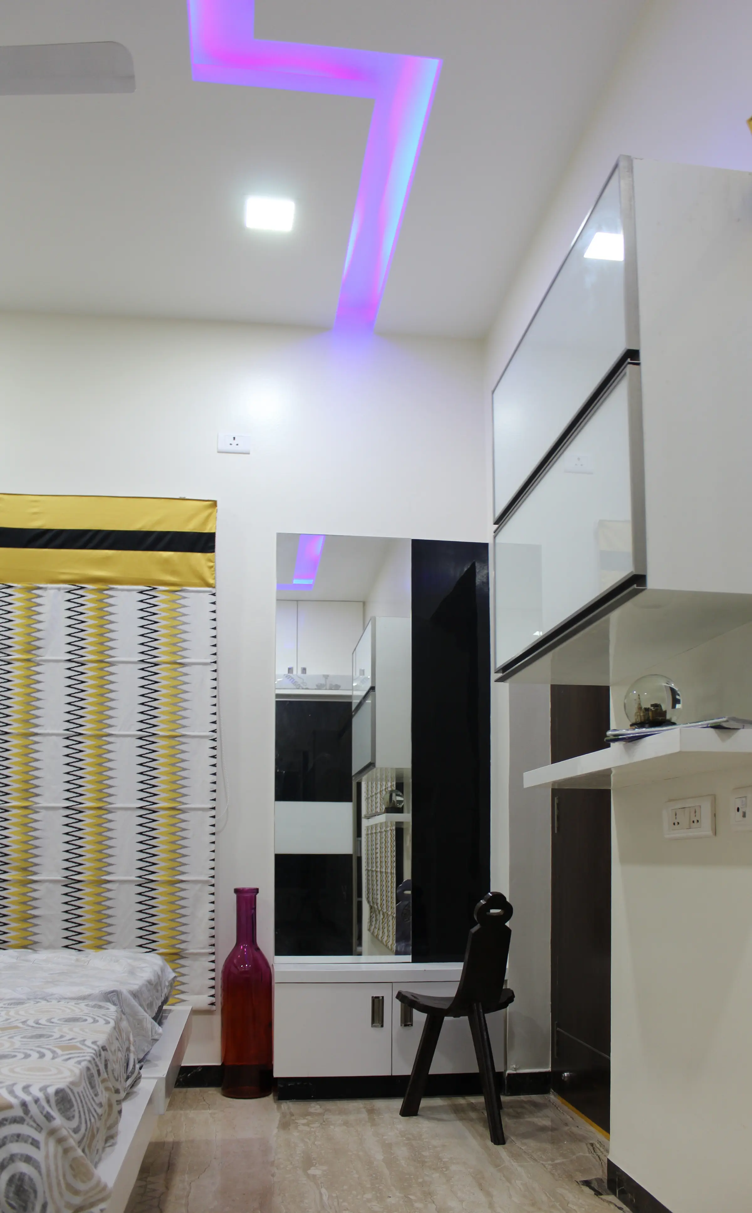 Dressing area with a full-height mirror, white cabinets and a purple cove light