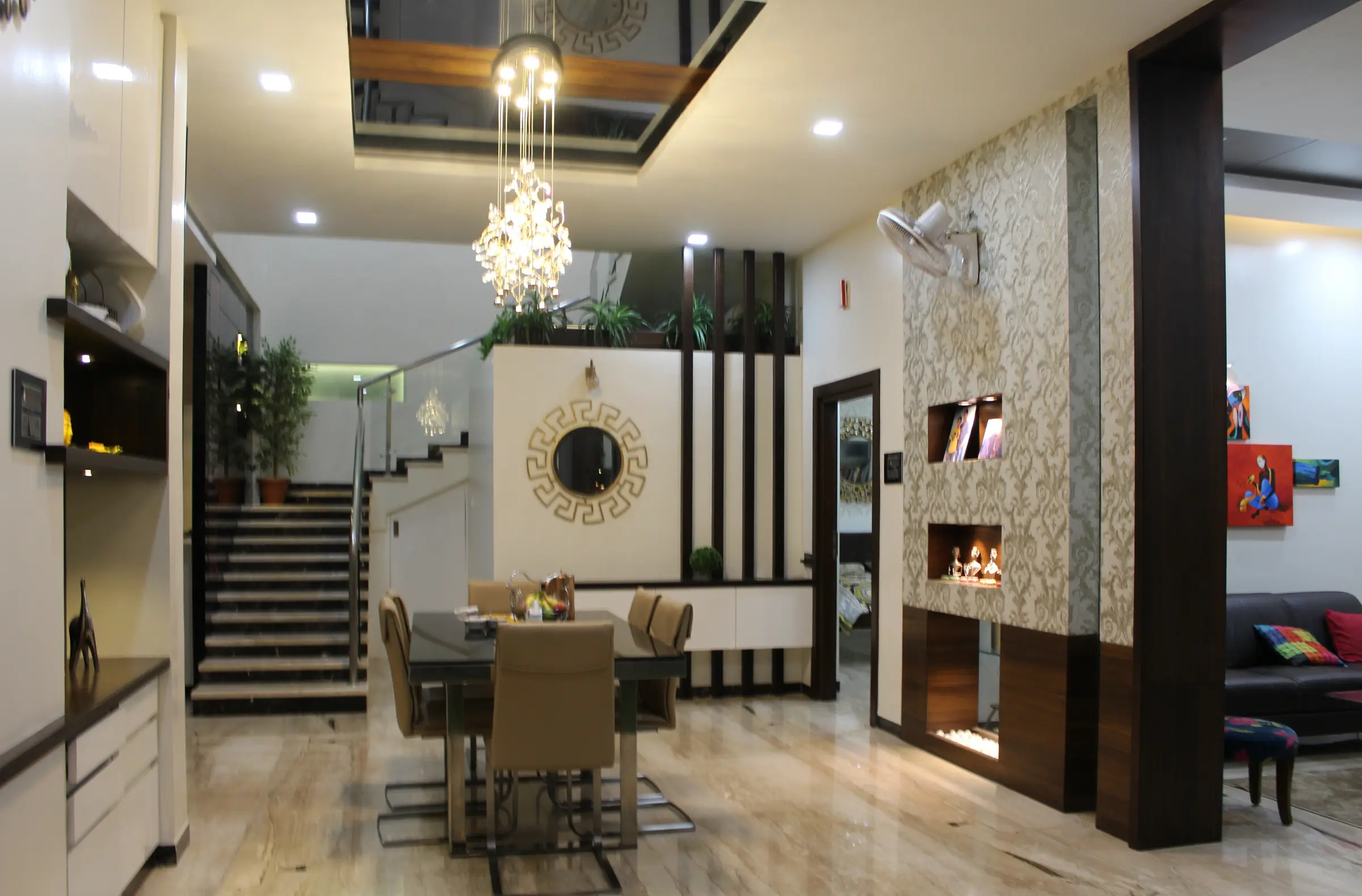 Double-height living and dining room with a chandelier, a floating staircase and a timber-and-stone feature wall