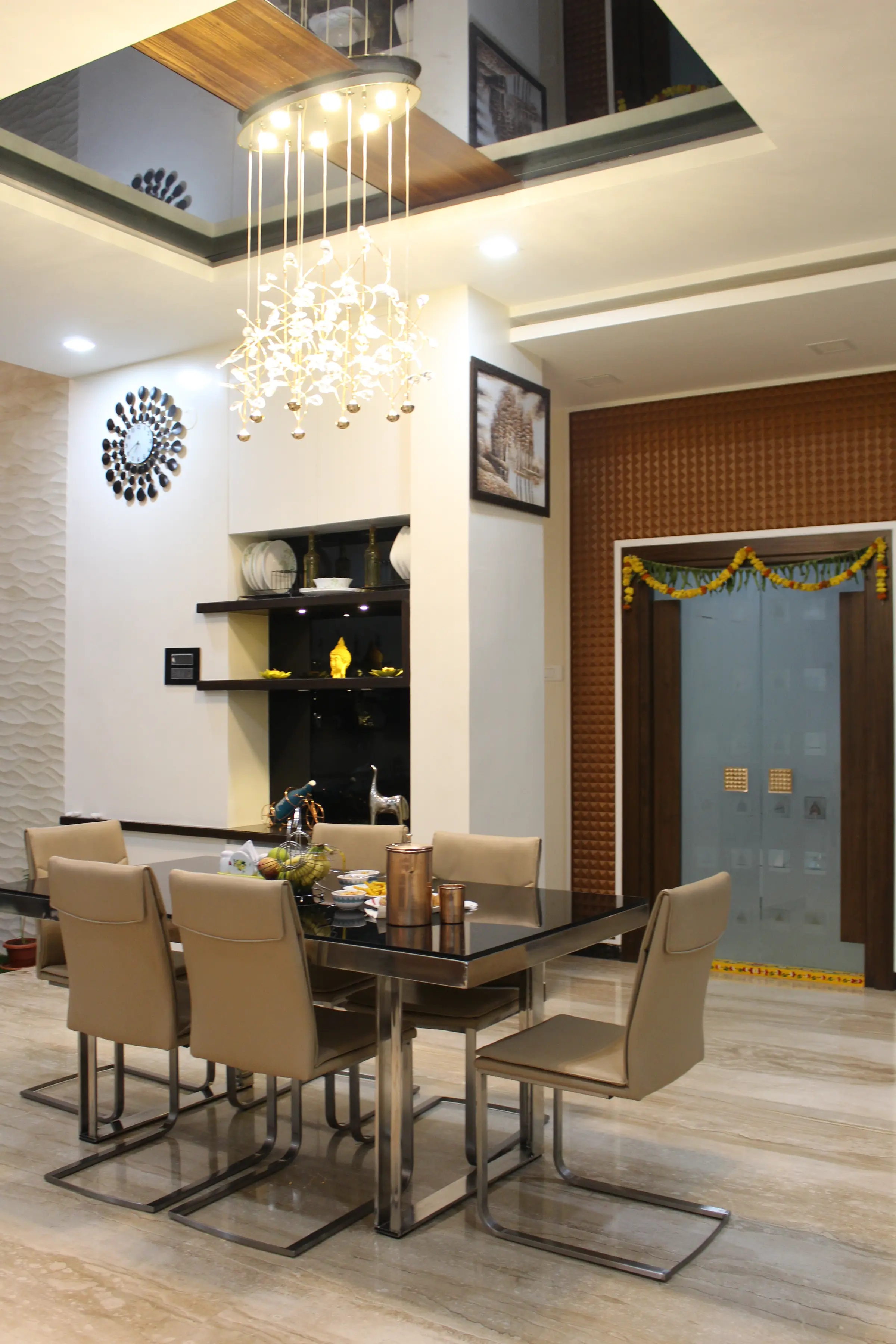 Dining table under a crystal chandelier, with a sunburst mirror and a garlanded doorway