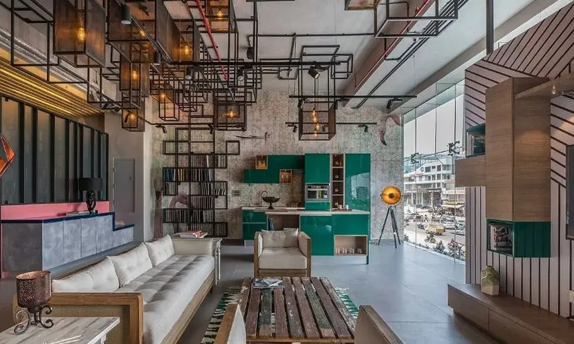 Kitchen showroom with a black steel grid ceiling, white sofas and a green display kitchen