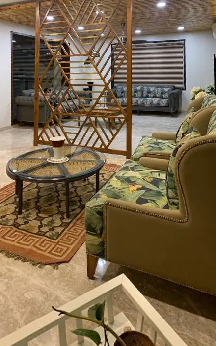 Lounge with a geometric timber screen, olive sofas and a round glass table
