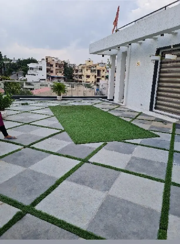 Roof terrace of grey stone pavers set in strips of grass