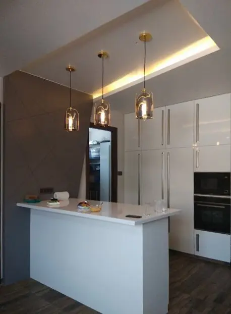 Kitchen with a white island, pendant lights and tall white cabinets