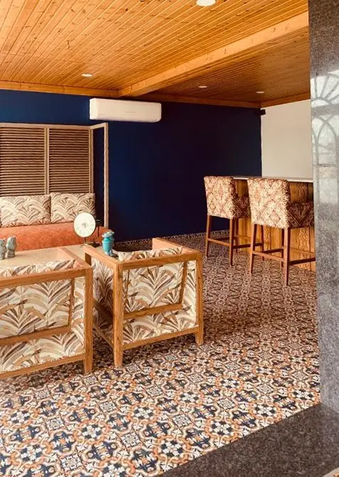 Sit-out with a timber ceiling, cane armchairs and a patterned cement-tile floor