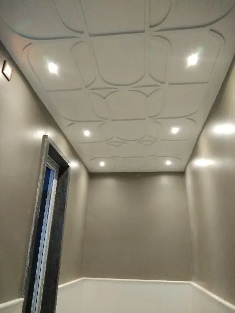 Room with a moulded white ceiling pattern and recessed lights
