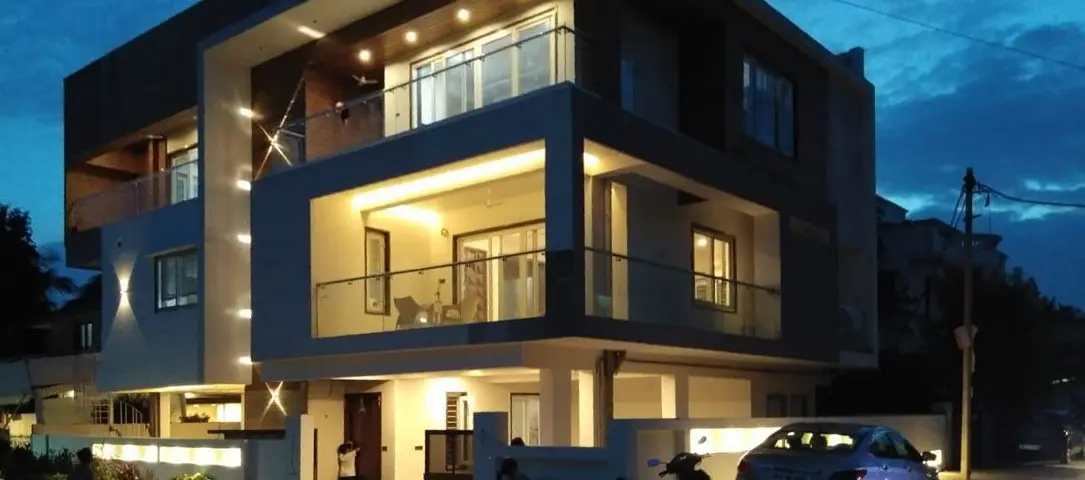 The villa at dusk, with its terraces and windows lit and a car at the gate