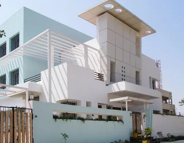 White villa with deep balconies, a pergola and a tall stair tower