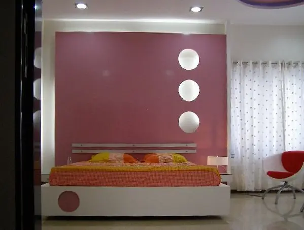 Bedroom with a pink feature wall, round lights and a white bed