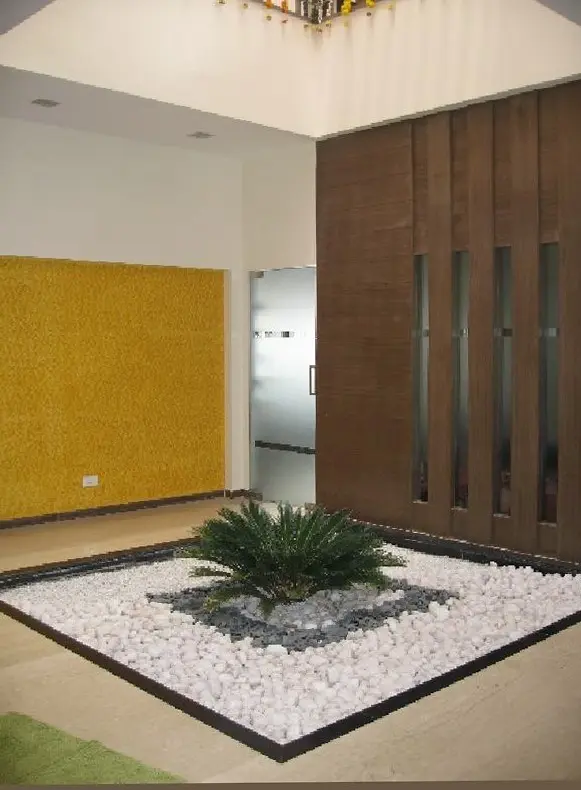 Indoor garden of white pebbles beside a yellow textured wall