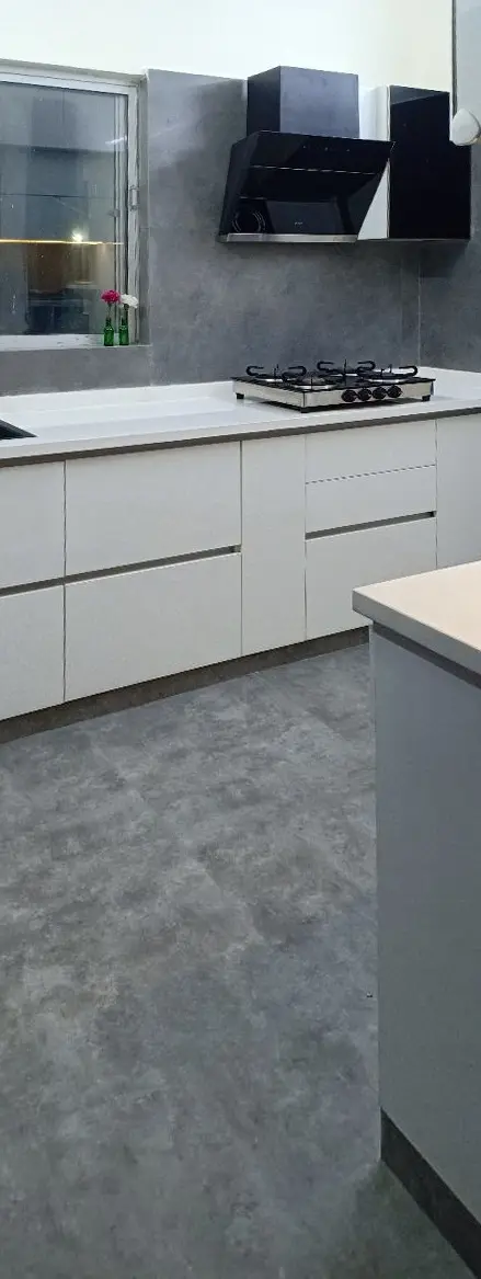 Galley kitchen with white cabinets and a black chimney hood