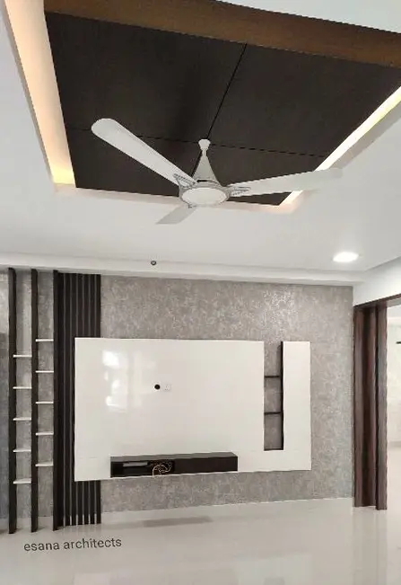 White TV wall with a black slatted panel under a lowered ceiling with cove light