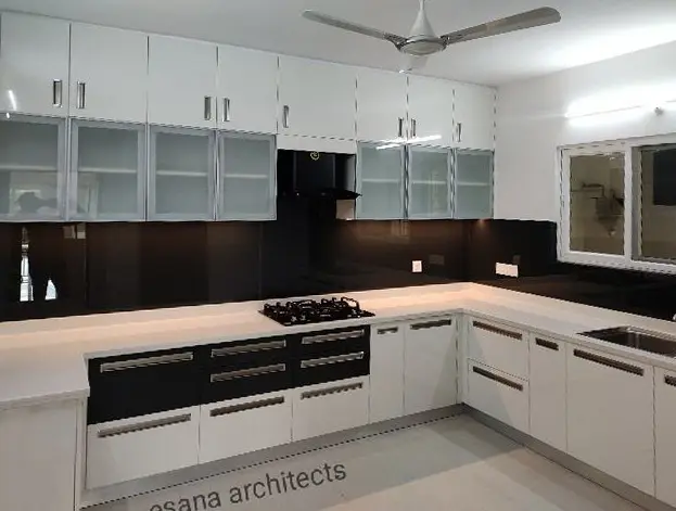White modular kitchen with a black glass backsplash and glass-fronted wall cabinets