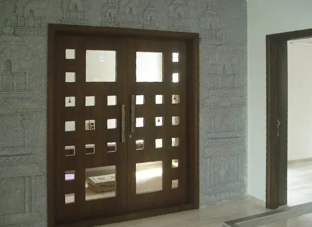 Timber double door with small square glass panes, set in a carved stone wall